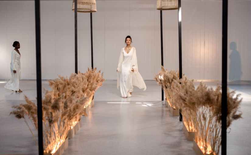 a model wearing a white dress walking on the runway