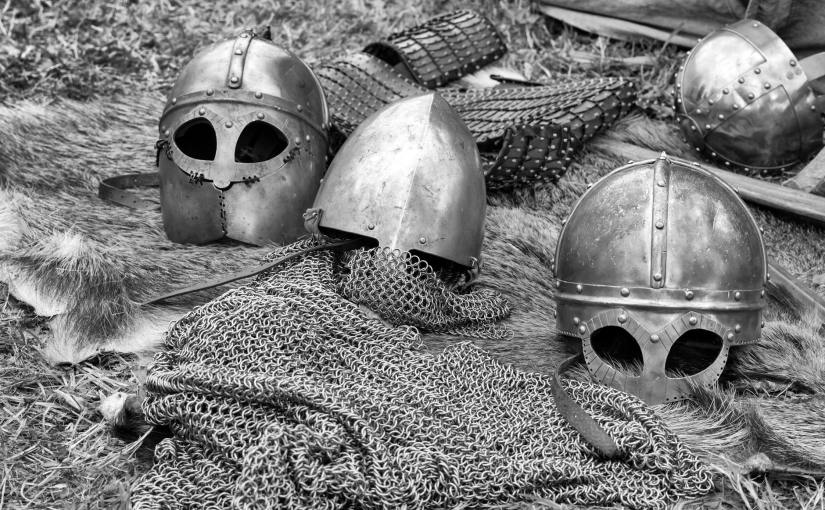 grayscale photography of chainmails and helmets on ground