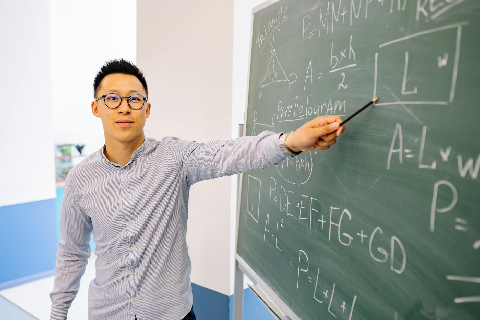 man wearing eyeglasses pointing at the blackboard