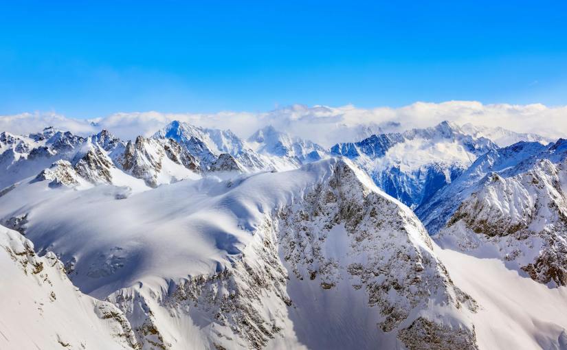 areal photography of snow coated mountains under clear blue sky