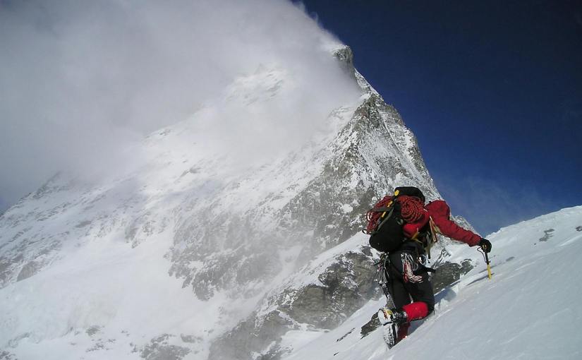 person climbing glacier mountain during day